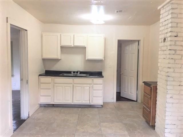 2921 NW 12th St, Oklahoma City, OK 73107 - kitchen with visible vents, white cabinetry, a sink, and dark countertops