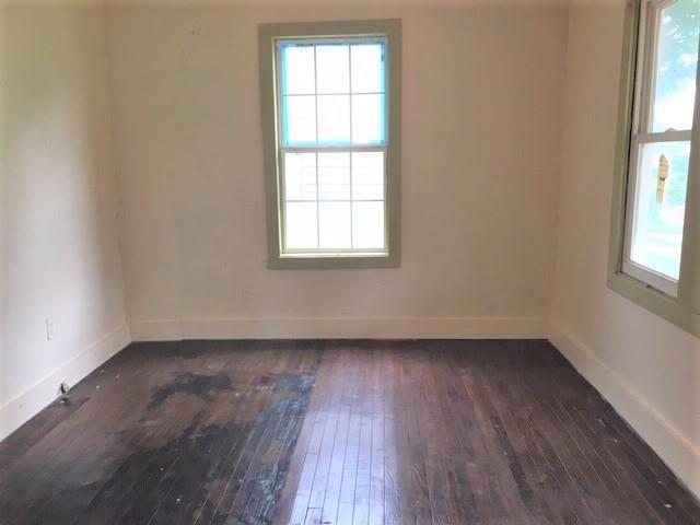 2921 NW 12th St, Oklahoma City, OK 73107 - empty room featuring plenty of natural light, dark wood-style floors, and baseboards