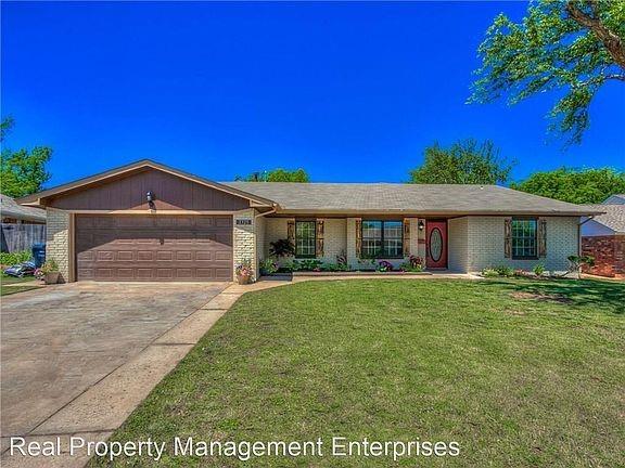 2325 NW 119th St, Oklahoma City, OK 73120 - ranch-style home with brick siding, concrete driveway, a garage, and a front lawn