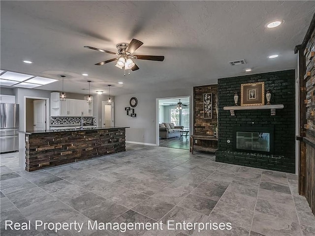 2325 NW 119th St, Oklahoma City, OK 73120 - unfurnished living room featuring a textured ceiling, visible vents, a brick fireplace, baseboards, and ceiling fan