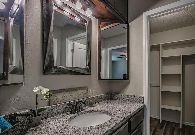 2325 NW 119th St, Oklahoma City, OK 73120 - bathroom featuring a textured wall, a textured ceiling, wood finished floors, and vanity