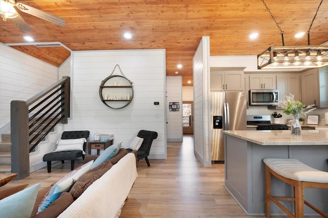 203 Secluded Cir, Broken Bow, OK 74728 - kitchen featuring appliances with stainless steel finishes, wooden ceiling, a kitchen breakfast bar, light wood-style floors, and light stone countertops