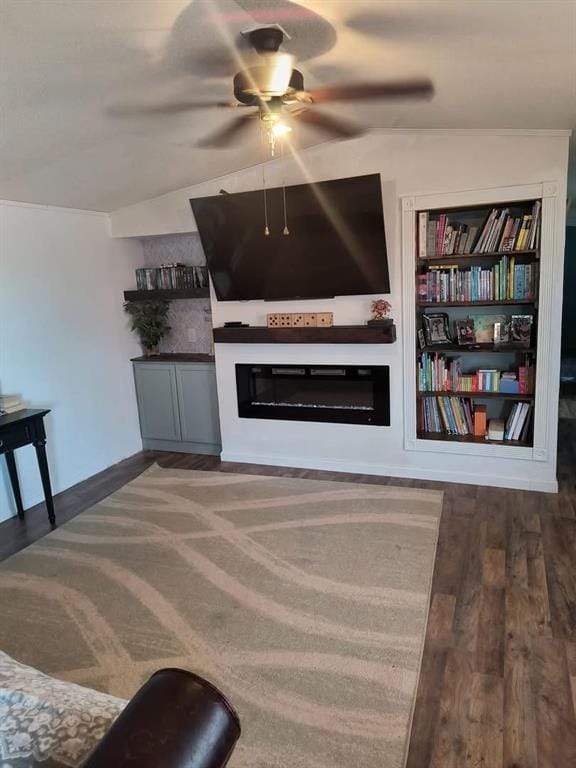 living area featuring a glass covered fireplace, lofted ceiling, a ceiling fan, and wood finished floors