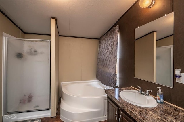 bathroom featuring a bath, a shower stall, a textured ceiling, and vanity