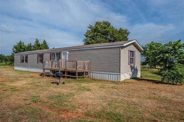 rear view of property featuring a wooden deck and a yard