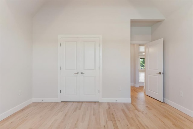 15632 Flora Ave, Edmond, OK 73013 - unfurnished bedroom with light wood finished floors, vaulted ceiling, baseboards, and a closet