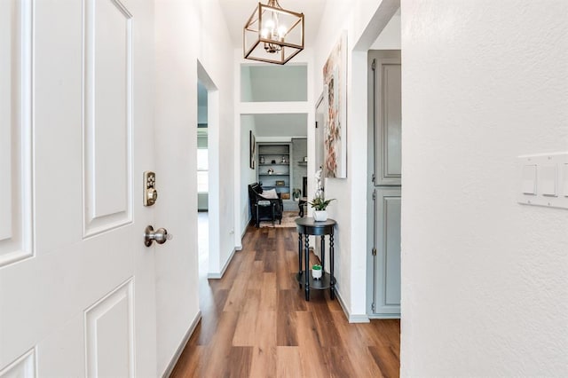 foyer with wood finished floors, baseboards, and an inviting chandelier