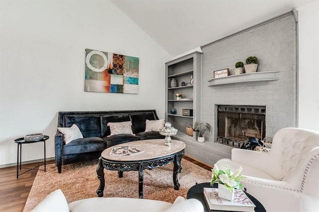 living room featuring baseboards, vaulted ceiling, wood finished floors, and a fireplace
