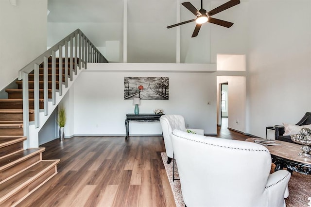 living area featuring ceiling fan, stairs, wood finished floors, and a towering ceiling