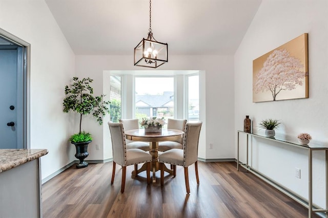 dining area with vaulted ceiling, wood finished floors, baseboards, and a notable chandelier