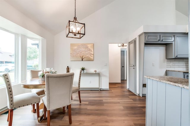 dining area with high vaulted ceiling, a chandelier, and wood finished floors
