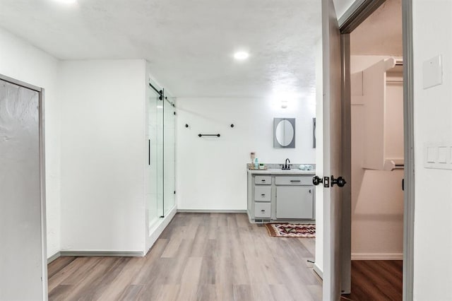 bathroom with baseboards, vanity, wood finished floors, and a stall shower