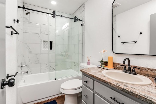bathroom with visible vents, combined bath / shower with glass door, vanity, and toilet