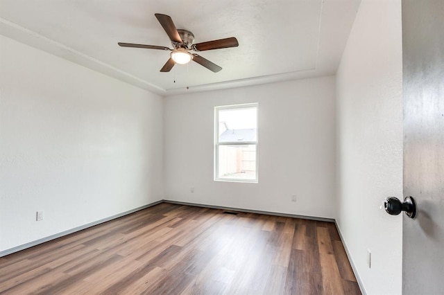spare room with visible vents, baseboards, wood finished floors, and ceiling fan