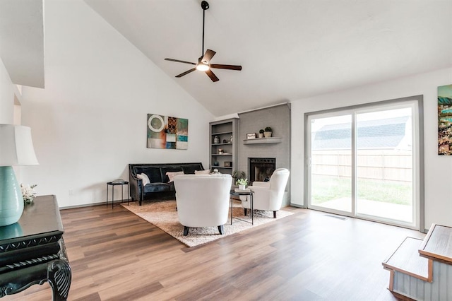 living room featuring baseboards, a ceiling fan, wood finished floors, a brick fireplace, and high vaulted ceiling