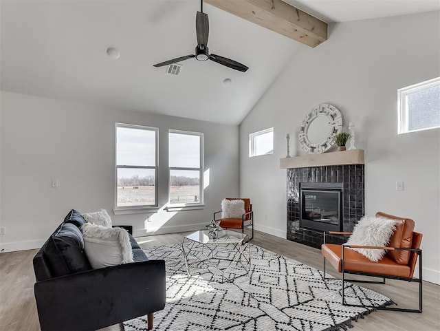 12909 NW 143rd St, Piedmont, OK 73078 - living area featuring beam ceiling, a tiled fireplace, a ceiling fan, baseboards, and wood finished floors