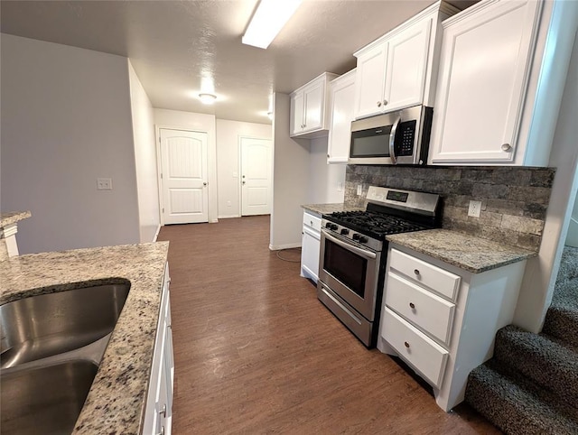 kitchen with decorative backsplash, dark wood-style flooring, white cabinets, and stainless steel appliances