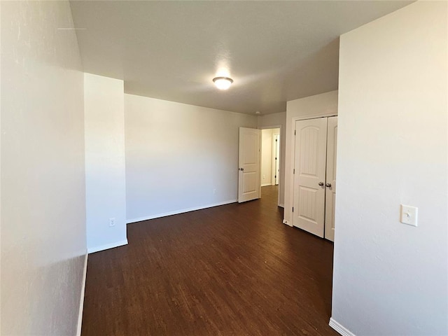 spare room featuring baseboards and dark wood-style flooring