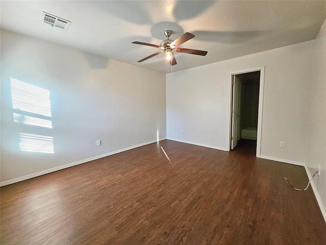 unfurnished room featuring dark wood finished floors, baseboards, visible vents, and ceiling fan