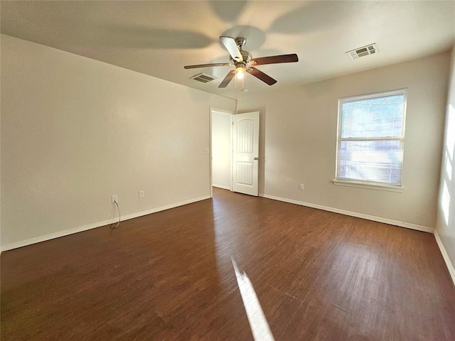 unfurnished room featuring dark wood-type flooring, baseboards, visible vents, and a ceiling fan