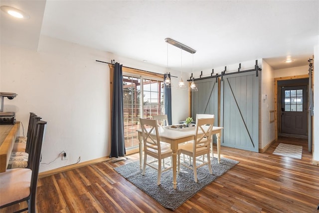 dining room featuring baseboards, a barn door, and wood finished floors