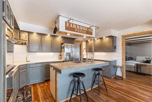 kitchen featuring a kitchen breakfast bar, a sink, stainless steel fridge with ice dispenser, and dark wood-type flooring