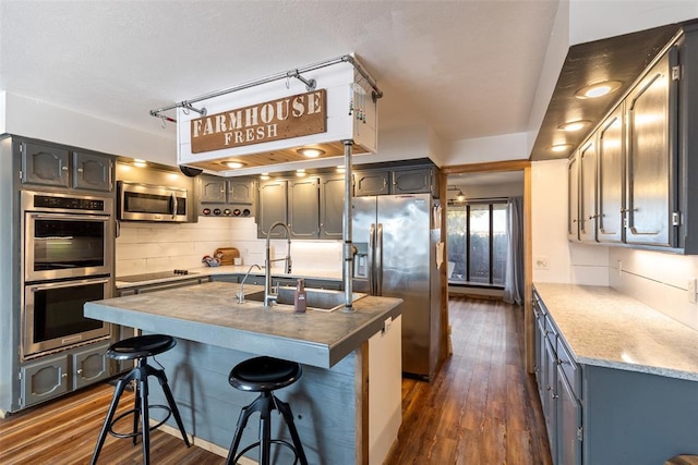 kitchen featuring dark wood-style floors, tasteful backsplash, a sink, and stainless steel appliances