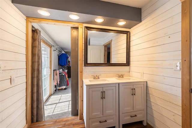 full bathroom featuring double vanity, a sink, and wooden walls