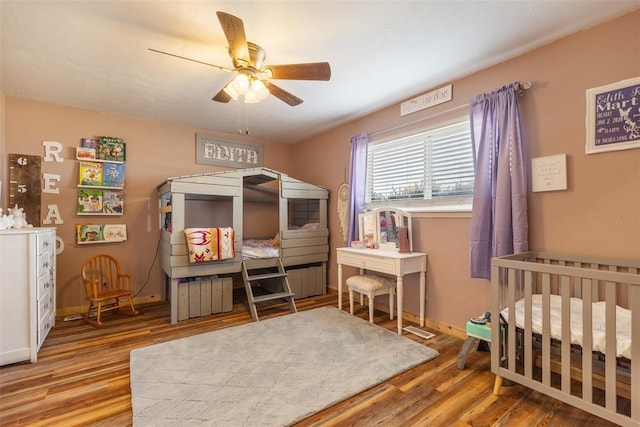 bedroom featuring baseboards, wood finished floors, and a ceiling fan