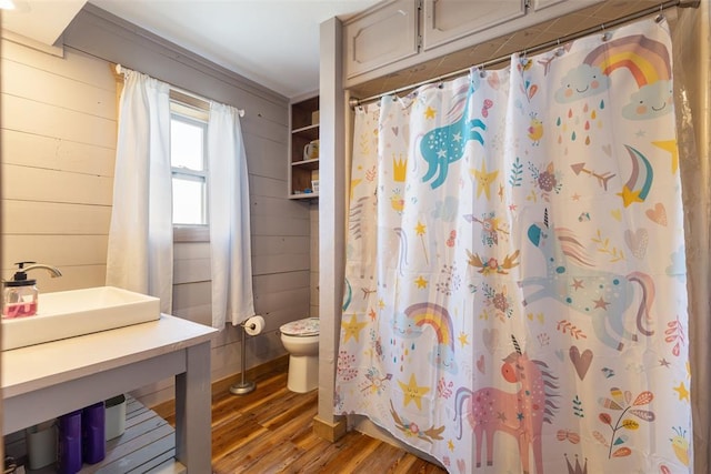 full bath featuring wood walls, toilet, a shower with curtain, and wood finished floors