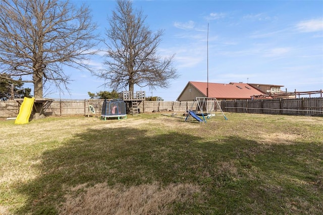 view of yard with a trampoline, a playground, and a fenced backyard