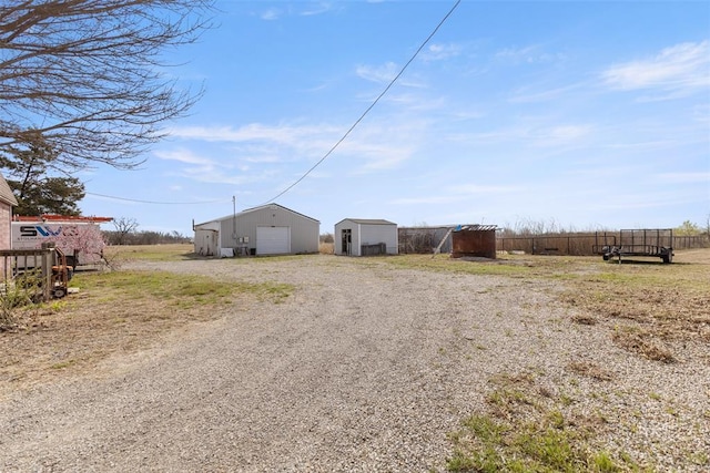 view of yard with an outdoor structure, driveway, fence, and a detached garage