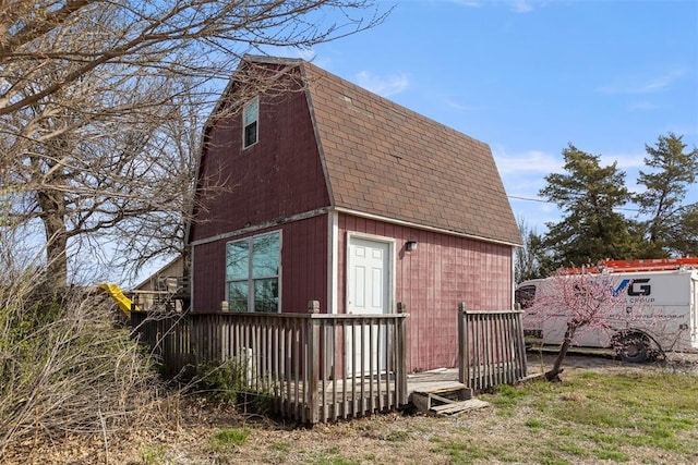 view of home's exterior featuring a shingled roof, a gambrel roof, and a deck