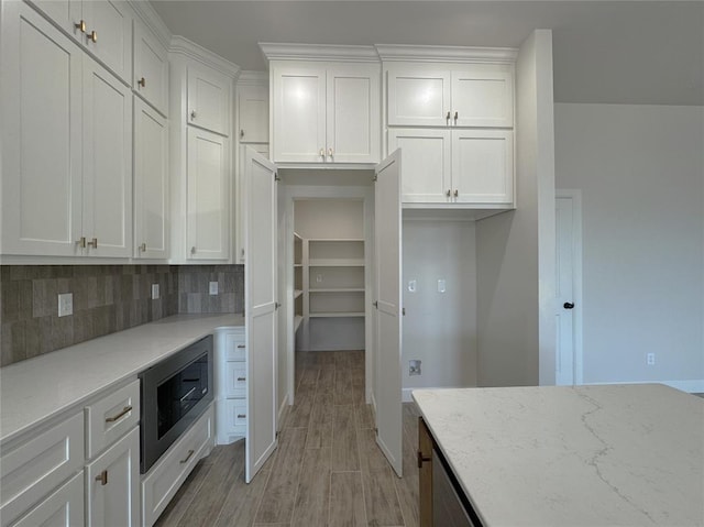 2420 Northfork Dr, Moore, OK 73160 - kitchen with built in microwave, white cabinets, light wood-style floors, and decorative backsplash