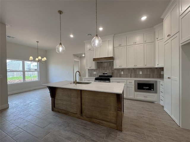 2420 Northfork Dr, Moore, OK 73160 - kitchen with stainless steel gas stove, a sink, tasteful backsplash, a chandelier, and premium range hood