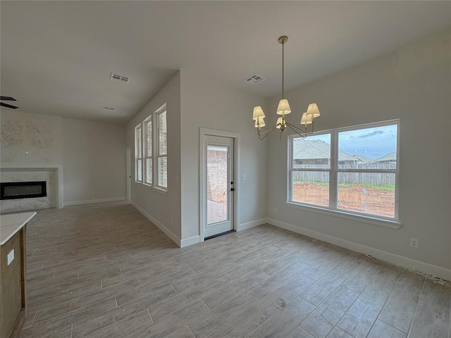 2420 Northfork Dr, Moore, OK 73160 - unfurnished dining area featuring light wood-style flooring, a chandelier, a fireplace, and baseboards