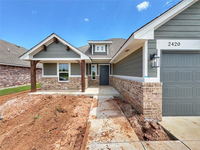 2420 Northfork Dr, Moore, OK 73160 - view of front of home featuring brick siding, covered porch, a garage, and roof with shingles