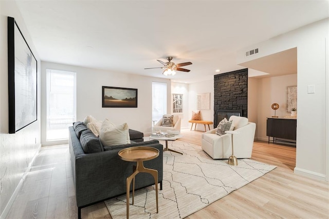 600 NW 4th St Unit 211N, Oklahoma City, OK 73102 - living room featuring light wood finished floors, a ceiling fan, a fireplace, and baseboards