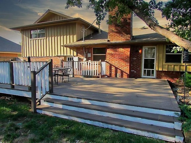 4700 NW 59th Ter, Oklahoma City, OK 73122 - back of house featuring board and batten siding, brick siding, a deck, and a chimney
