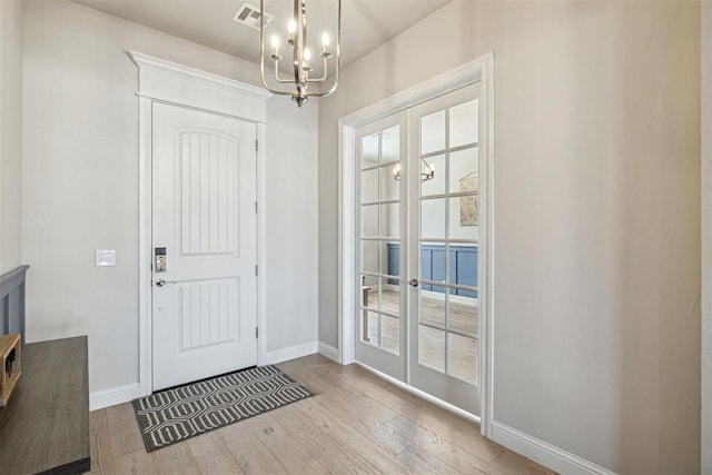 entrance foyer with french doors, baseboards, visible vents, a notable chandelier, and wood finished floors