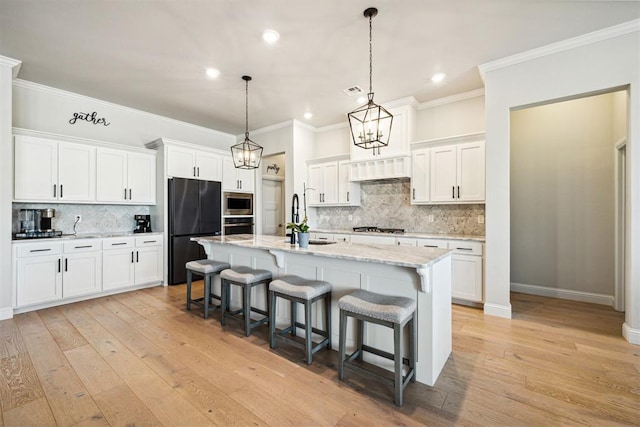 kitchen featuring white cabinets, light wood-style flooring, a breakfast bar, ornamental molding, and stainless steel appliances