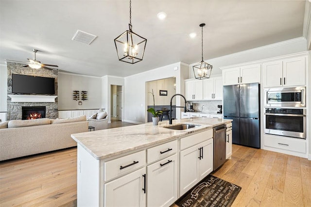kitchen with crown molding, ceiling fan with notable chandelier, a sink, visible vents, and appliances with stainless steel finishes
