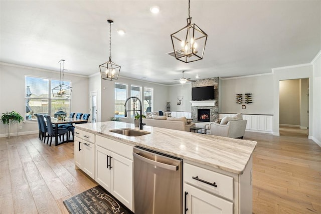 kitchen featuring a healthy amount of sunlight, light wood-type flooring, a sink, dishwasher, and a stone fireplace