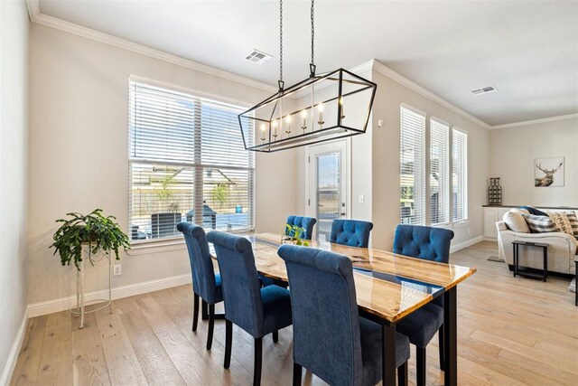 dining space with plenty of natural light, ornamental molding, visible vents, and light wood-type flooring