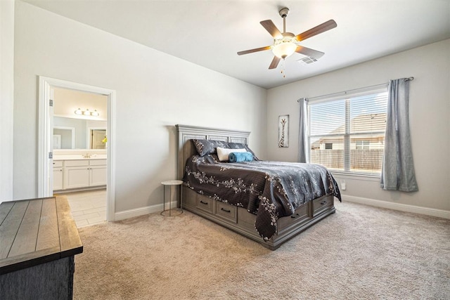 carpeted bedroom featuring baseboards, a sink, ceiling fan, visible vents, and ensuite bathroom