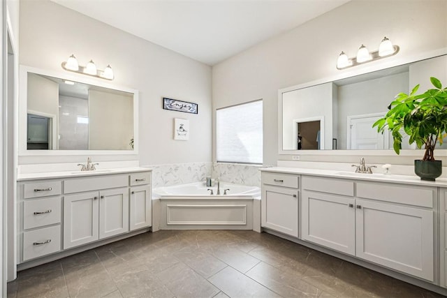 full bathroom featuring a bath, a sink, and two vanities