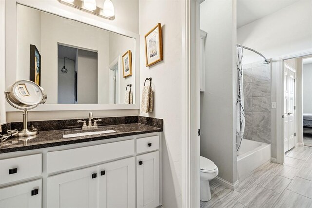 bathroom with baseboards, toilet, shower / bath combo with shower curtain, and vanity