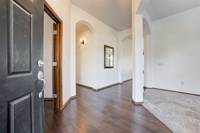 entryway featuring arched walkways, baseboards, and dark wood finished floors