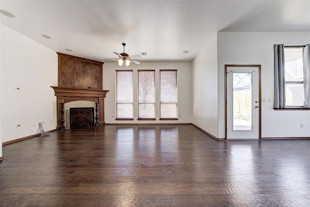 unfurnished living room with visible vents, baseboards, ceiling fan, a fireplace, and dark wood-type flooring