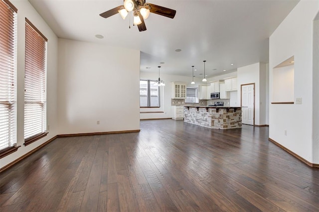 unfurnished living room with baseboards, ceiling fan, recessed lighting, and dark wood-style flooring
